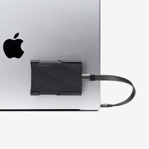 Close-up of Samsung SCREENMOUNT securing a Samsung T-series drive to a silver Apple laptop for organized connectivity.
