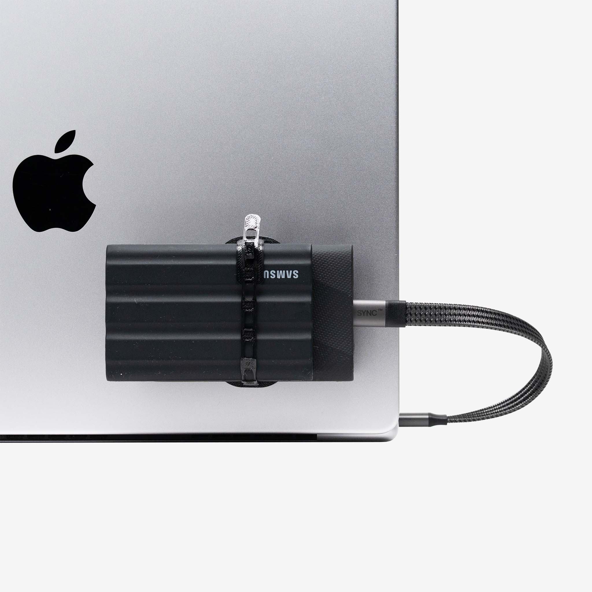 Universal SCREENMOUNT securely attached to a laptop holding a Samsung external drive to prevent dangling drives.