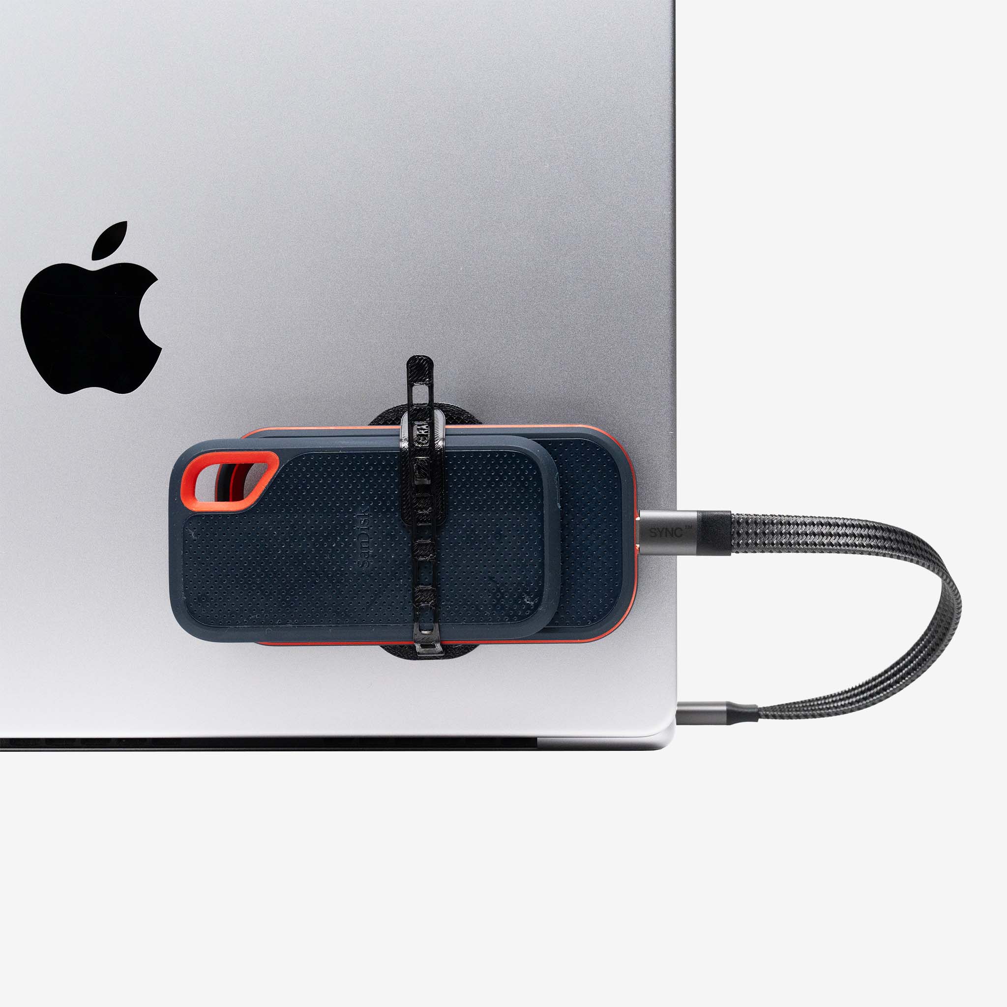 Universal SCREENMOUNT attached to a laptop securely holding an external drive with a braided data cable plugged in